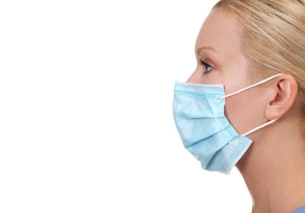 Profile image of young female nurse Profile image of young female nurse wearing face mask isolated on white surgical mask stock pictures, royalty-free photos & images