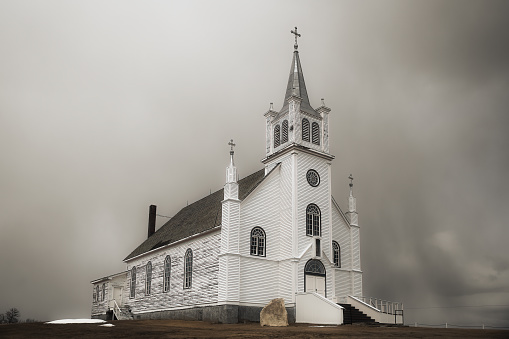 A beautiful old church with peeling paint along the side and a refinished front in a springtime countryside landscape