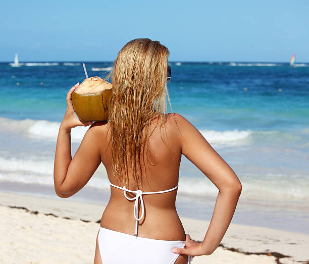 Woman holding coconut on the beach stock photo