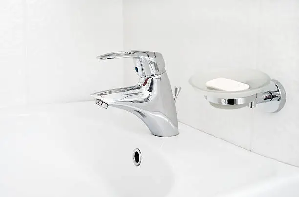One chrome faucet in washbowl in bath room o white pile with soap holder