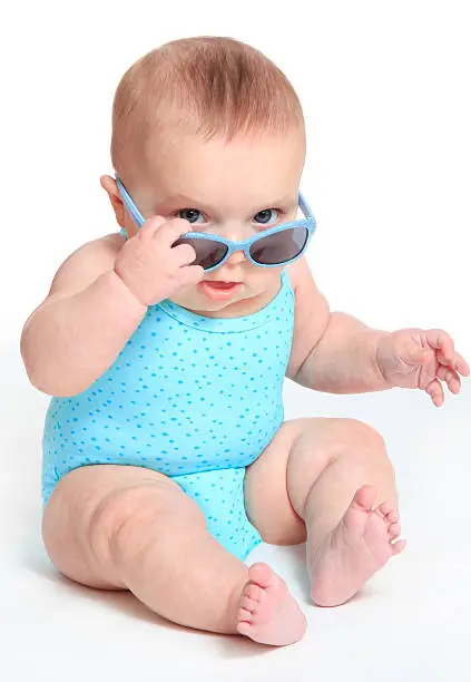 Photo of Baby girl wearing a blue swimsuit and sunglasses