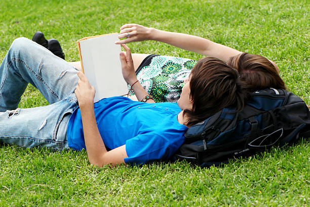 istock Couple students laying on the grass and reading a book 176803061