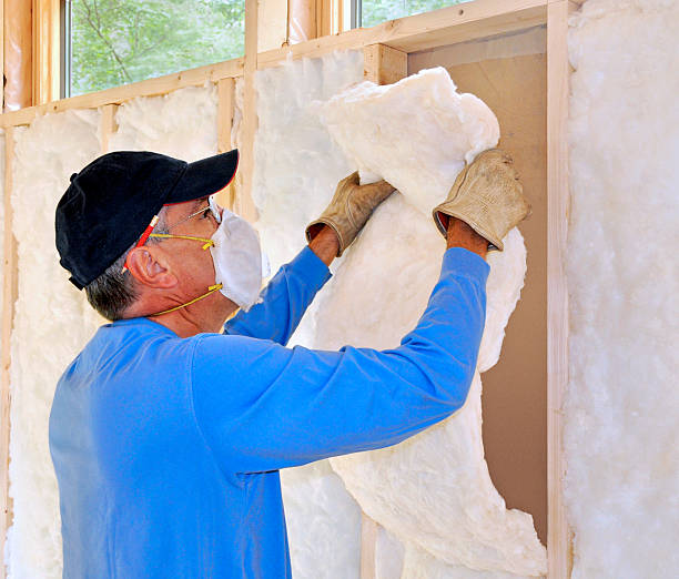 Technician in mask installing fiberglass insulation stock photo