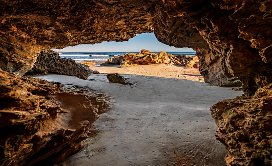 Natural cave erosion in rock arch on sandy beach
