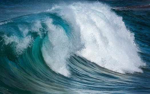 Blue water big waves crashing and curving towards beach