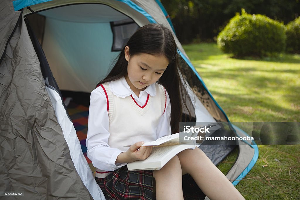 little girl reading in a tent 10-year old little asian girl is sitting in a tent and reading a book. click here for more Camping Stock Photo