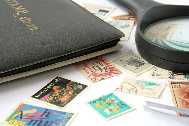 "Various stamps, stamp album, magnifying glass and tweezers"