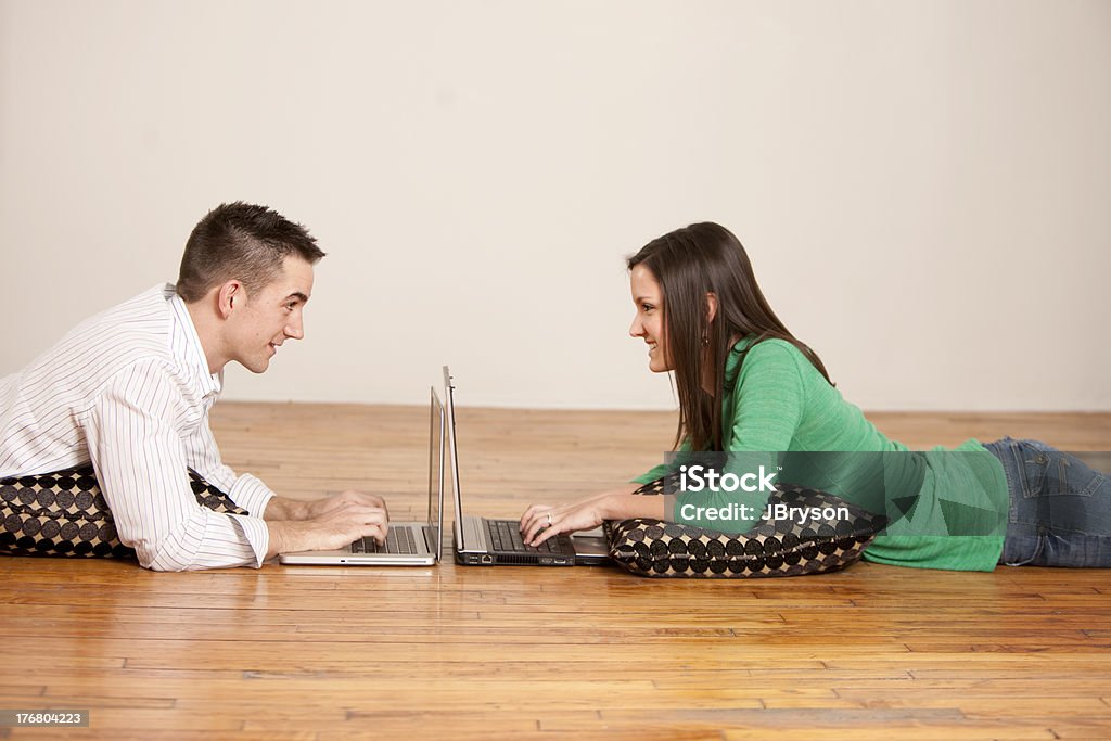 Coppia di fronte a vicenda mentre si lavora su computer - Foto stock royalty-free di Computer portatile