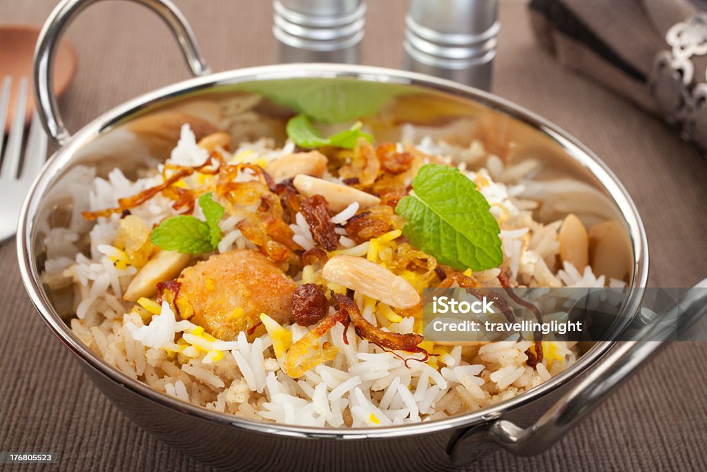 A close-up of a bowl of Chicken Biryani on a rice pillau Indian special occasion dish, chicken biryani is garnished with crisp fried onions, sultanas, almonds and mint.  More curry here. Balti Dish Stock Photo