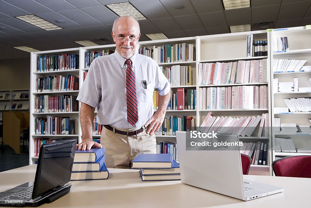 Portrait of mature man at library table with textbooks "Portrait of mature man at library table with textbooks, professor researching" 50-54 Years Stock Photo