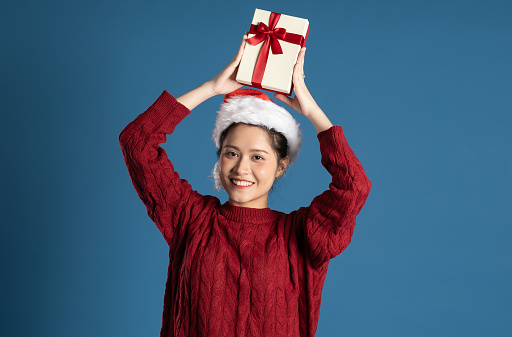 Beautiful woman wearing Santa hat isolated on blue wall