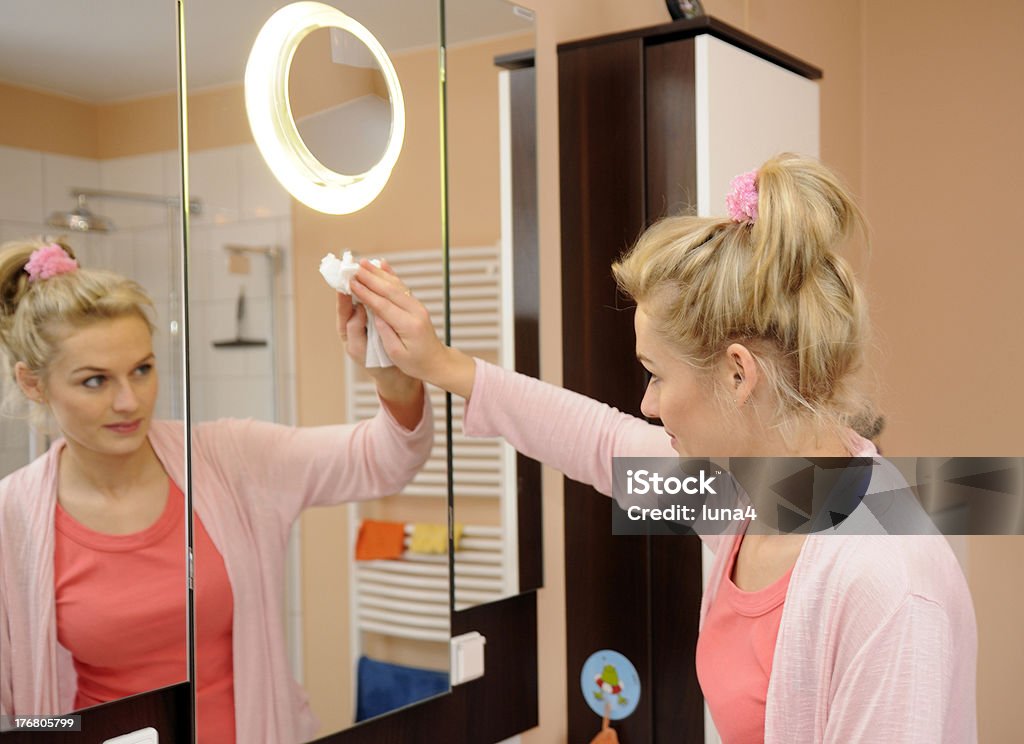 housewife cleans a mirror beautiful blond housewife cleans a mirror in the bathroom Adult Stock Photo