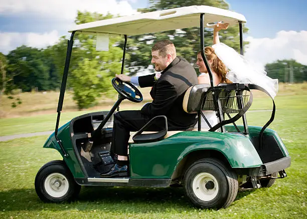 Fun, action packed image of a bride and groom zooming away on a golf cart. Speaks to the concepts of eloping and getting away from it all, and the fun couples have at their weddings. 