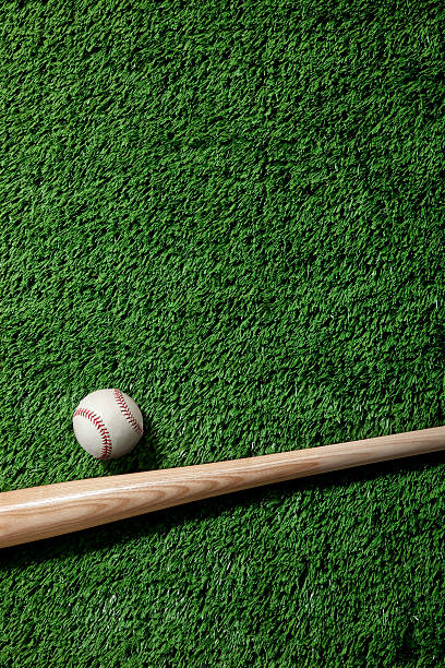 istock A baseball and wooden bat on artificial green grass 176807651