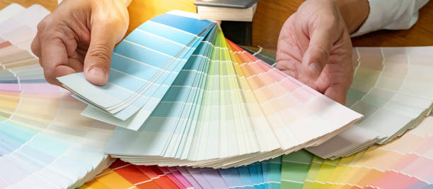 istock Designer hand choosing color swatch samples catalog or rainbow colour palette guide for selection coloring on architecture and interior design work. 1768081295