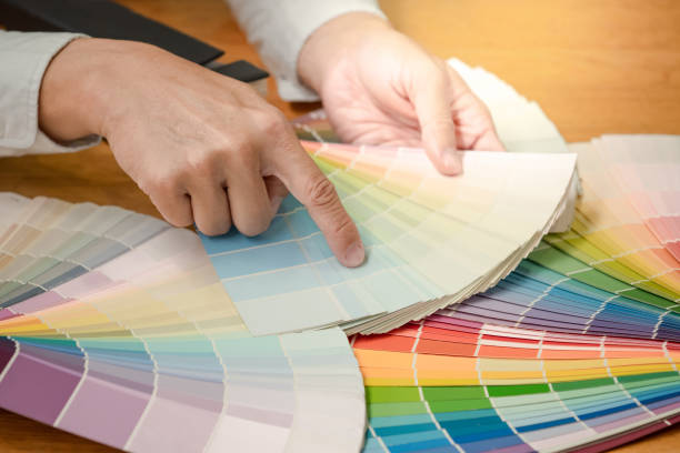 istock Designer hand choosing and pointing at color swatch samples catalog or rainbow colour palette guide for selection coloring on architecture and interior design work. 1768081874