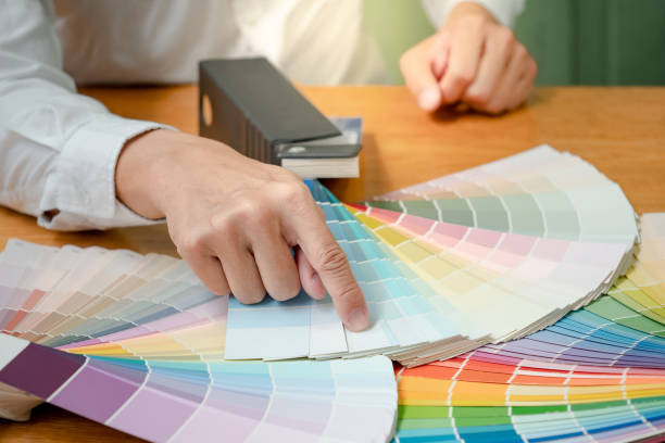 istock Designer hand choosing and pointing at color swatch samples catalog or rainbow colour palette guide for selection coloring on architecture and interior design work. 1768082976
