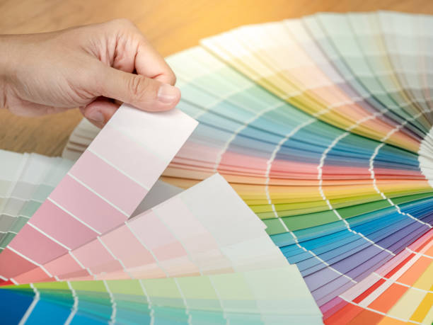istock Designer hand choosing and pointing at color swatch samples catalog or rainbow colour palette guide for selection coloring on architecture and interior design work. 1768082992