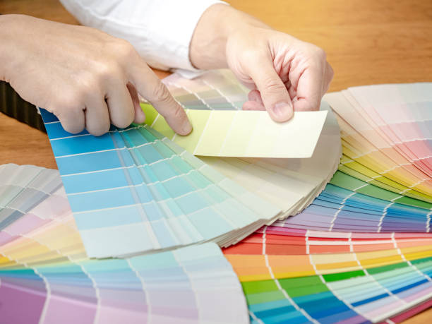 istock Designer hand choosing and pointing at color swatch samples catalog or rainbow colour palette guide for selection coloring on architecture and interior design work. 1768083524