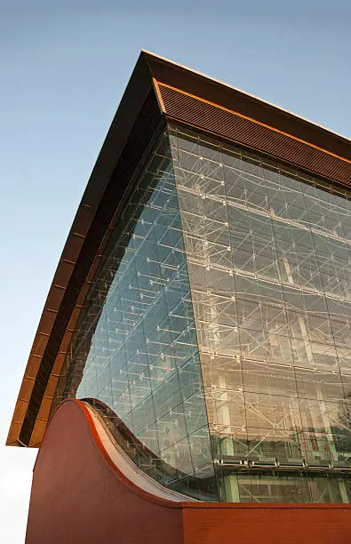 Modern futuristic industrial architecture.Power plant building with wave shaped metal roof with glass wall and arch brickwall with blue sky at sunrise.Similar Images: