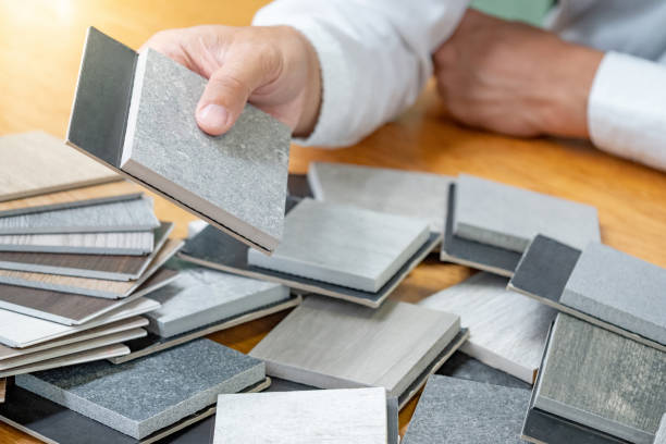 istock Architect hand choosing sample of stone and wood material or tile texture collection on the table in studio. Designer working for interior architecture and furniture design project. 1768085608