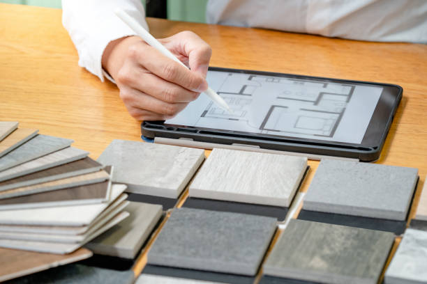 istock Architect hand choosing stone and wood material samples while drawing on a digital tablet on the table in studio. Designer working for interior architecture and furniture design project. 1768085623
