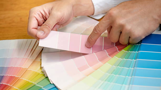 istock Designer hand choosing and pointing at color swatch samples catalog or rainbow colour palette guide for selection coloring on architecture and interior design work. 1768087264