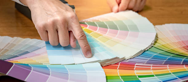 istock Designer hand choosing and pointing at color swatch samples catalog or rainbow colour palette guide for selection coloring on architecture and interior design work. 1768087818