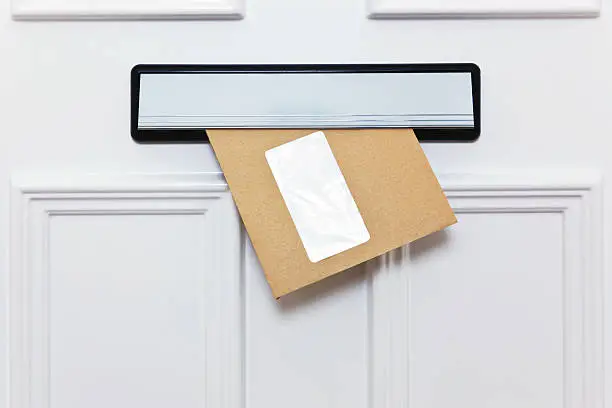 Brown envelope in a front door letterbox blank window for you to add your own name and address details.