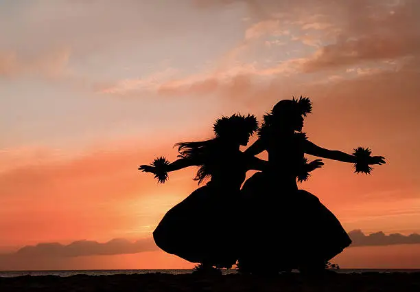 Two Hawaiian hula dancers move gracefully before the warm glow of the tropical sunset.