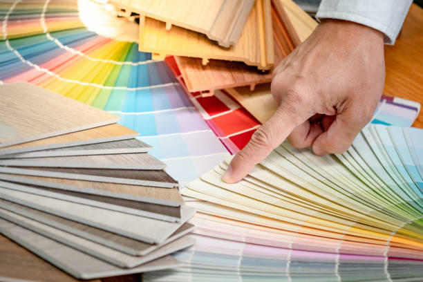 istock Designer hand choosing and pointing at color swatch with wood laminate material samples and wooden tile texture collection nearby. Catalog guide for interior architecture and furniture design work 1768090874