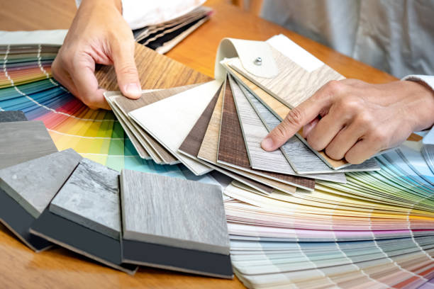 istock Designer hand choosing and pointing at wood laminate material samples with color swatch and wooden tile texture collection nearby. Catalog guide for interior architecture and furniture design work 1768092404