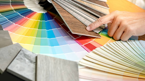 istock Designer hand choosing and pointing at wood laminate material samples with color swatch and wooden tile texture collection nearby. Catalog guide for interior architecture and furniture design work 1768092410