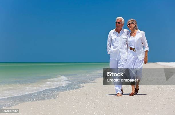 Feliz Pareja Senior Caminando Por Una Playa Tropical Foto de stock y más banco de imágenes de Pareja mayor
