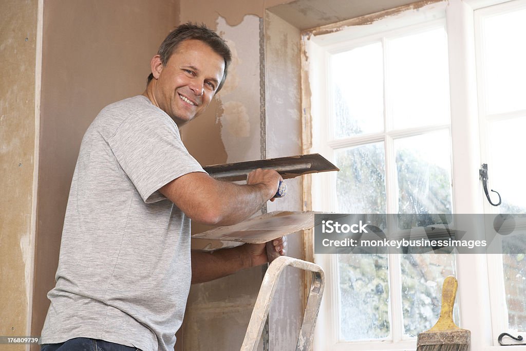 Plasterer Working On Interior Wall Plasterer Working On Interior Wall near window Plasterer Stock Photo