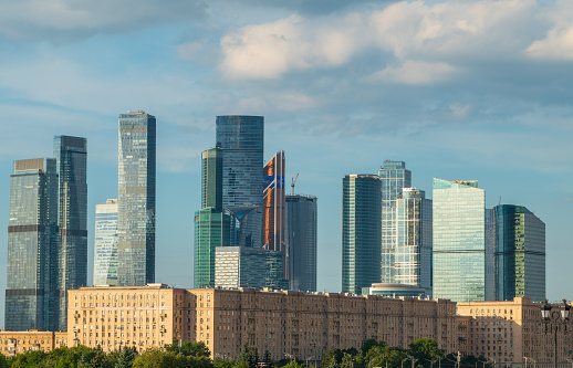 Green trees on background modern skyscrapers in the Moscow city. Panorama of new Moscow City buildings in spring