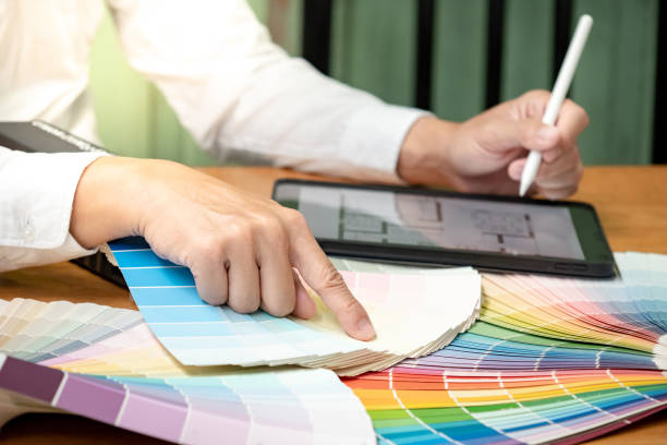 istock Designer hand choosing and pointing at color swatch or rainbow colour palette guide while working on digital tablet. Selection coloring for architecture and interior design work. 1768103014