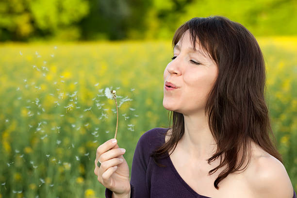 istock woman blowing dandelion 176810954