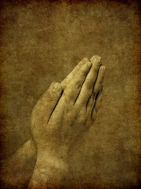 A set of praying hands - image has been textured and distressed to simulate an old and aged ambrotype photo from the Victorian era.
