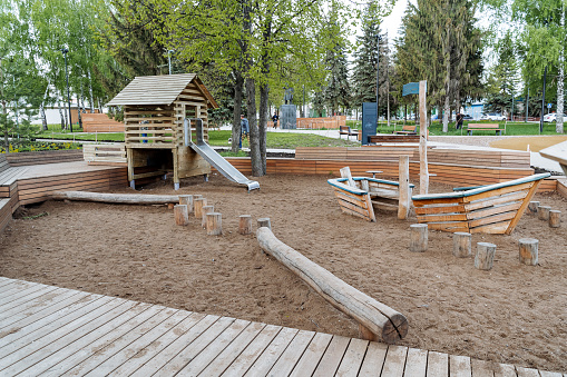 Children's playground of large sizes, sandbox in the yard, wooden boat for games, a house with a slide, rest with a child on the street. High quality photo