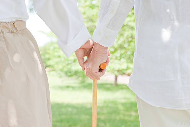 A close-up of a person helping an elderly person with a cane stock photo