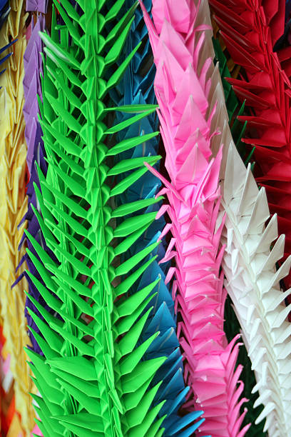 Artistic Origami papercraft parrots perched on white desk lamp, set against blurred home office background, evoke creativity, childhood and brightness. Hobbies.