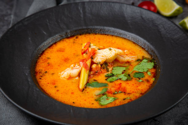 istock spicy tom yum in a black plate with greens, side view 1768143297
