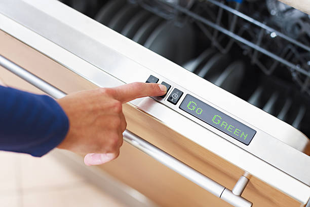 woman pressing energy saver button on dishwasher stock photo