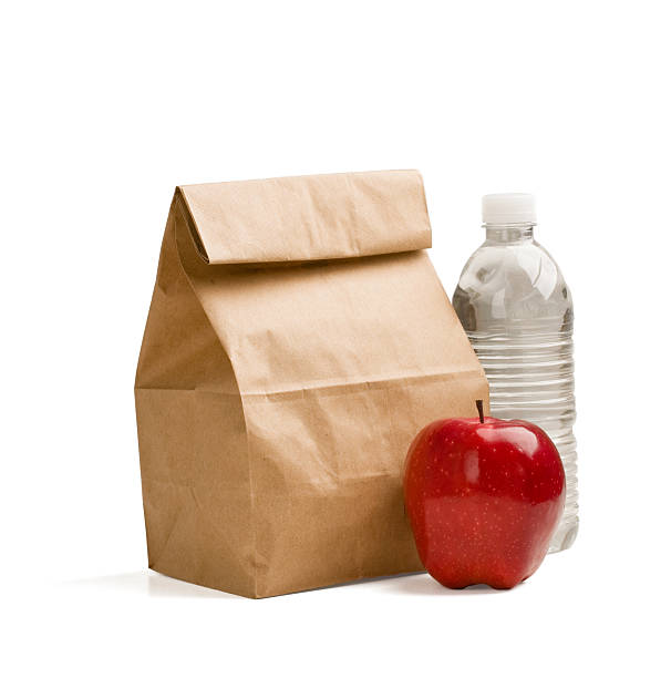 Brown bag lunch with red apple and water bottle Brown paper lunch bag, red apple and bottle of drinking water isolated on white background.  packed lunch photos stock pictures, royalty-free photos & images