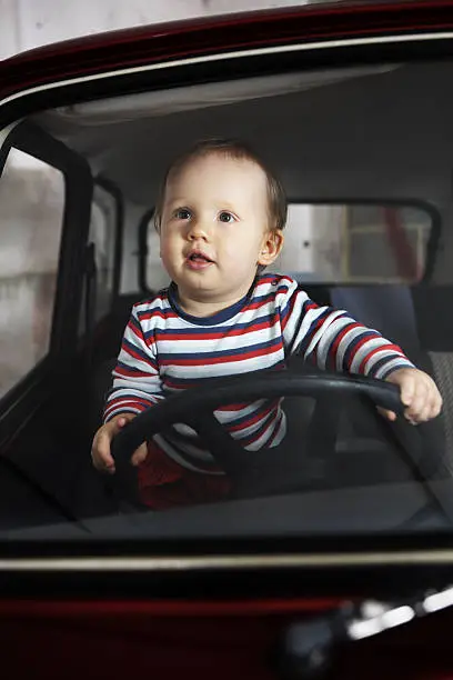 Photograph through windscreen of a baby dreaming of taking a car for a joyride.