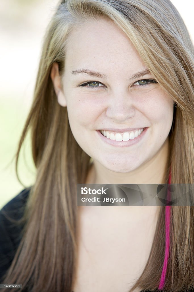 Real People: Head Shoulders Smiling Caucasian Teenage Girl "A head and shoulders image of a smiling caucasian real teenage girl. The image is outdoors on a sunny day in the park.  Extreme shallow depth of field," Close-up Stock Photo