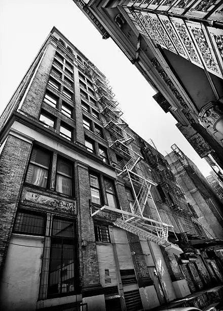 Perspective view of NYC building exterior with fire escape, Black and white.