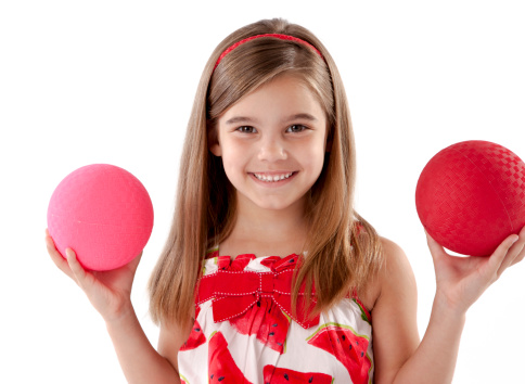 Headshot of adorable little girl balancing two playground balls.