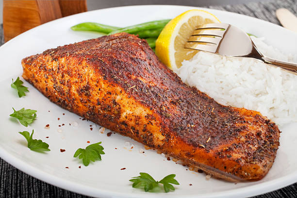 Cajun blackened salmon served with rice and lemon on a plate "Salmon steak with Cajun seasoning, grilled and served with rice. Sometimes called blackened redfish." cajun food photos stock pictures, royalty-free photos & images